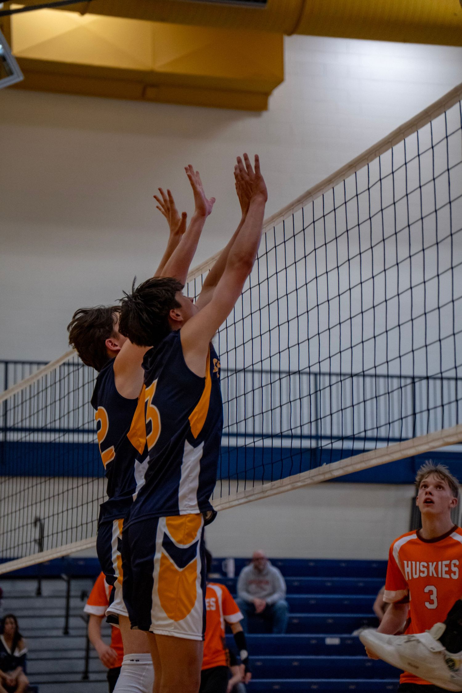 Two players jumping in unison to block at the volleyball net.
