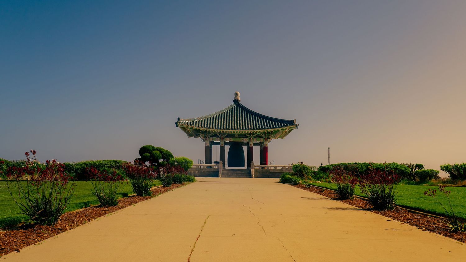Traditional Asian architecture panorama showing a pagoda-style building on a concrete plaza.