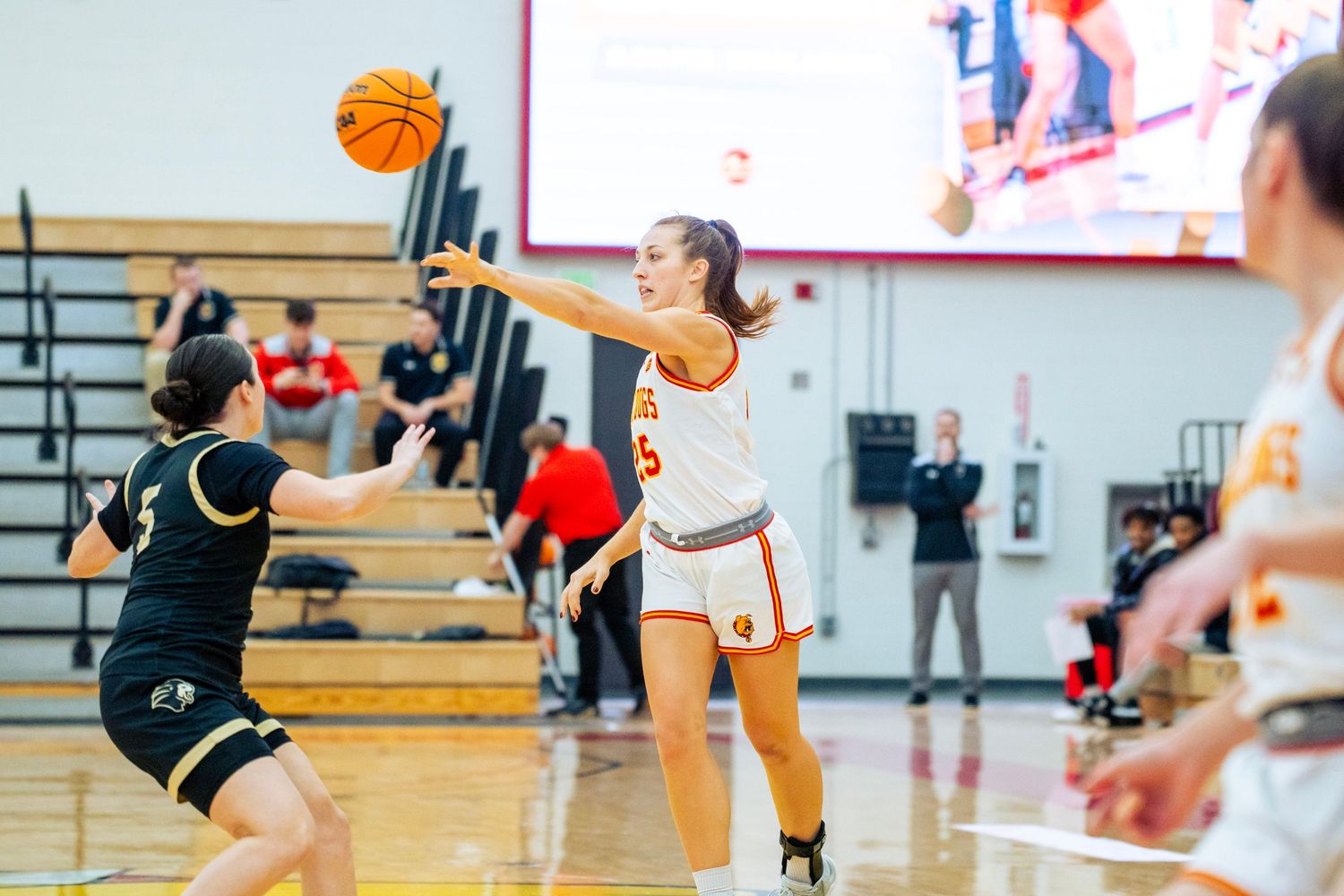 Basketball players compete for possession during an intense game on a gymnasium court.