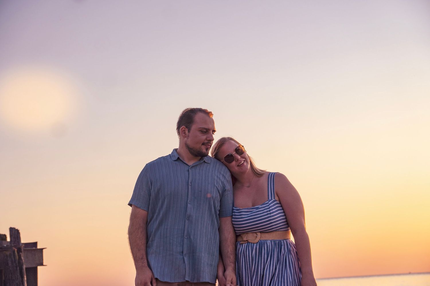 A couple enjoys a romantic moment together against a warm sunset sky on a beach.
