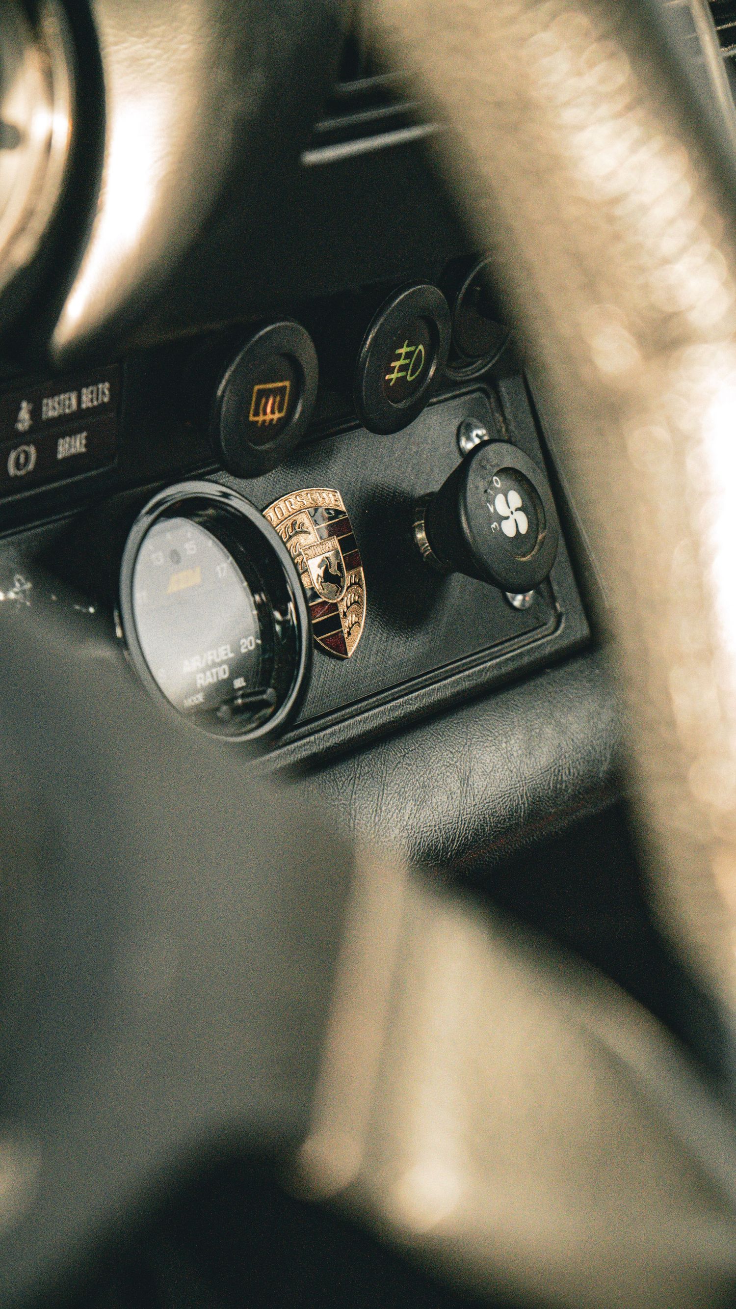 Interior detail of a Porsche dashboard showing control buttons and badges.