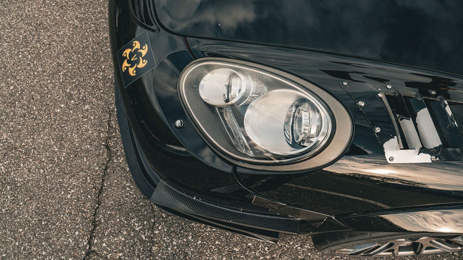 Close-up detail shot of black sports car headlights and front bumper.