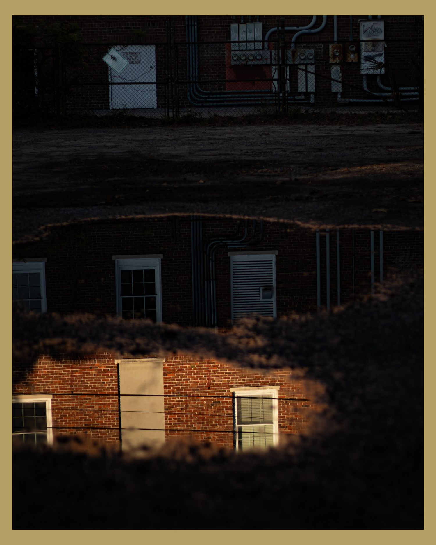 Sunlight dramatically illuminating brick building windows in dark setting.