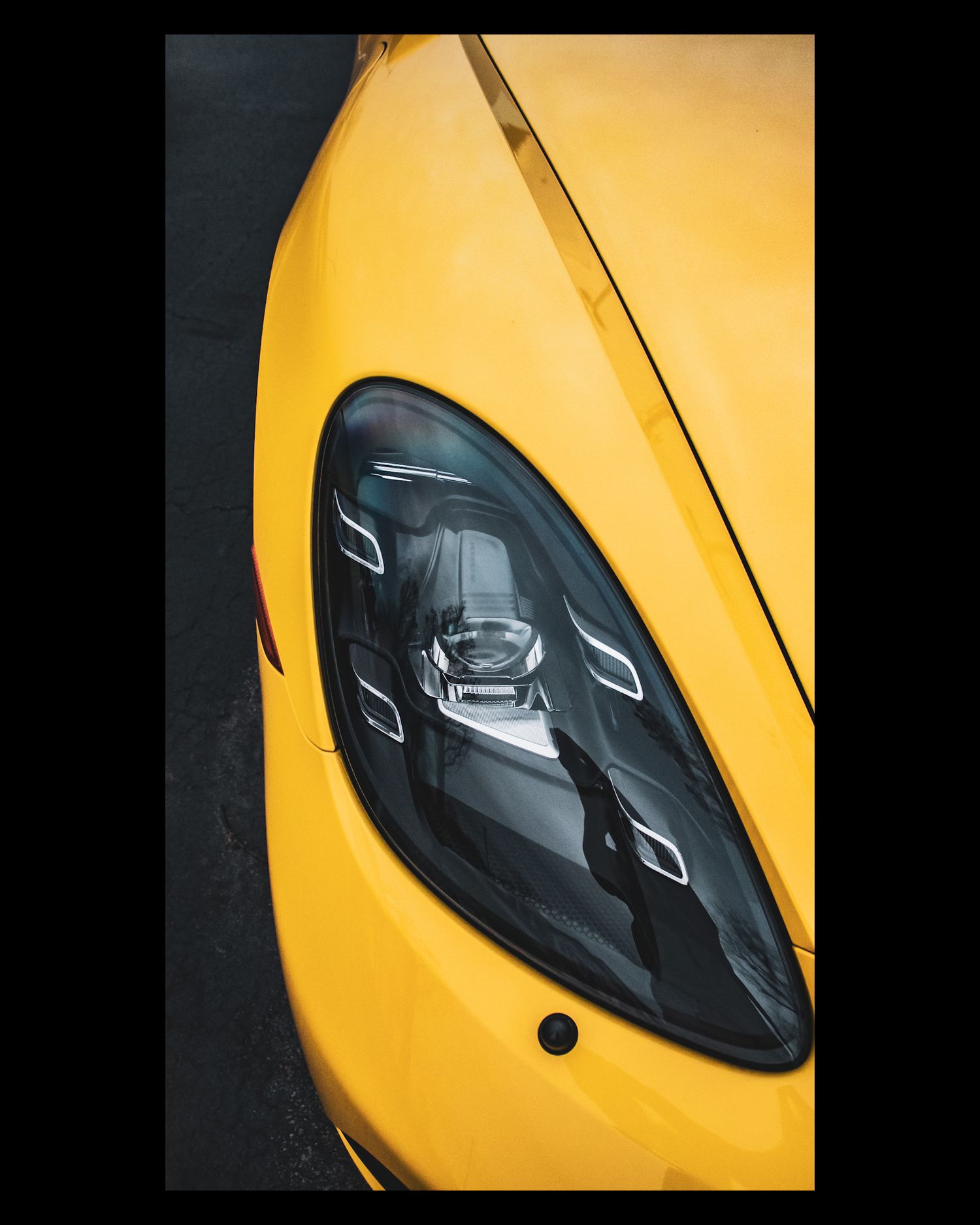 Close-up detail shot of a modern yellow sports car headlight with distinctive LED design.