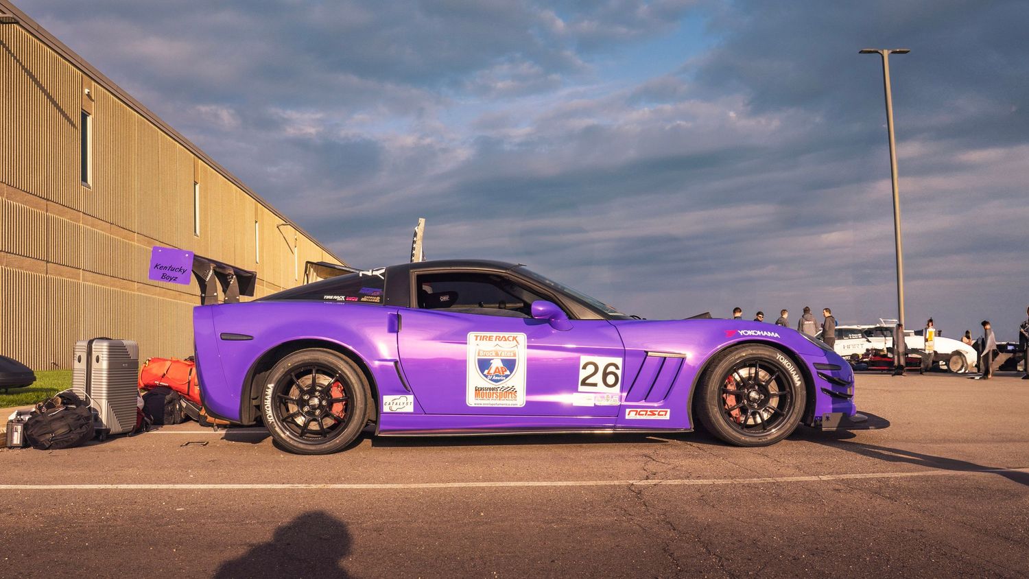 Side profile of a purple Corvette race car with racing livery and black wheels.