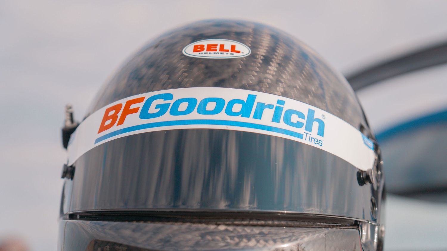 Close-up of a Bell racing helmet with BFGoodrich branding against a blurred background.