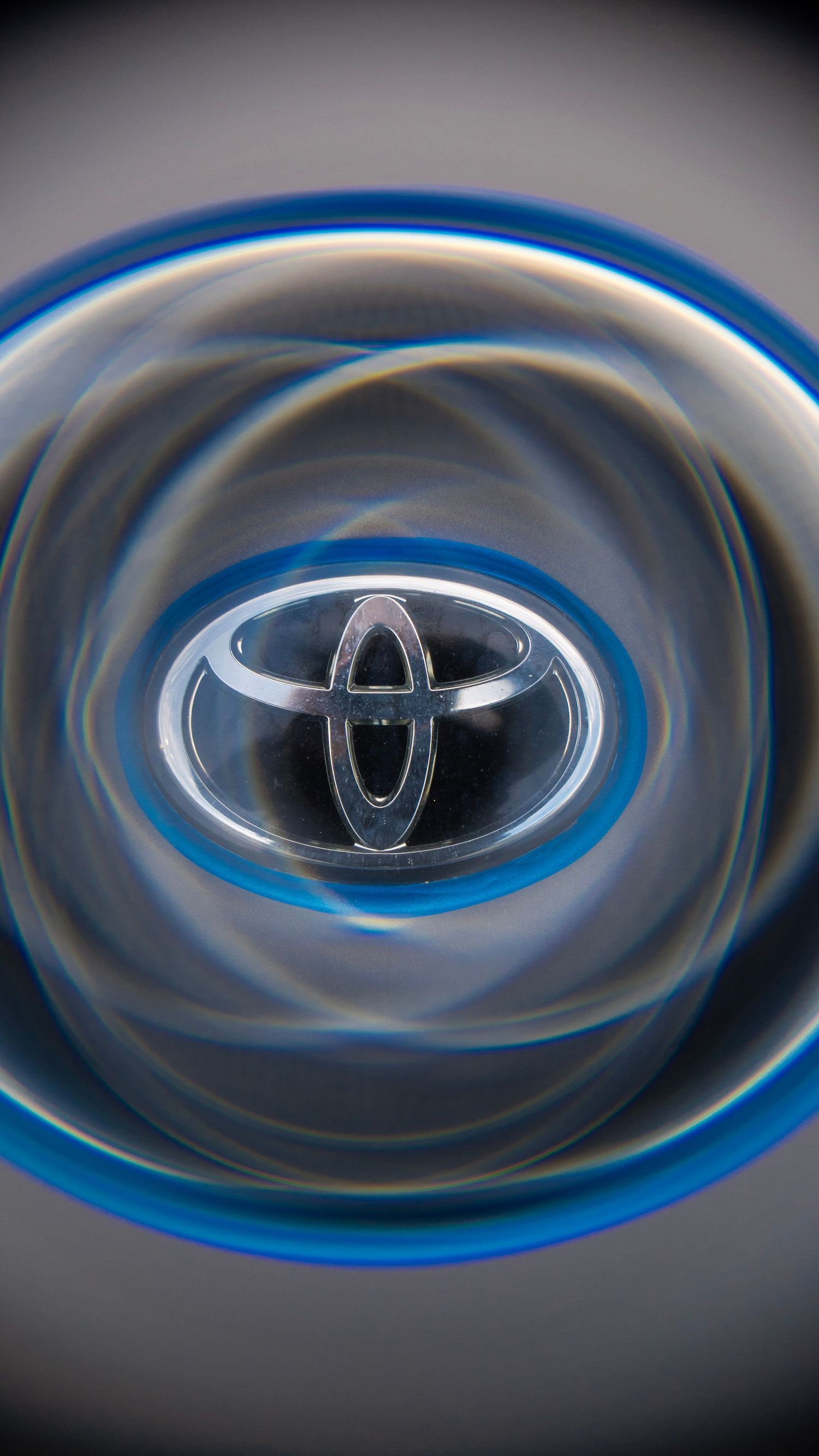 Toyota logo emblem distorted through a swirling blue and grey vortex effect.