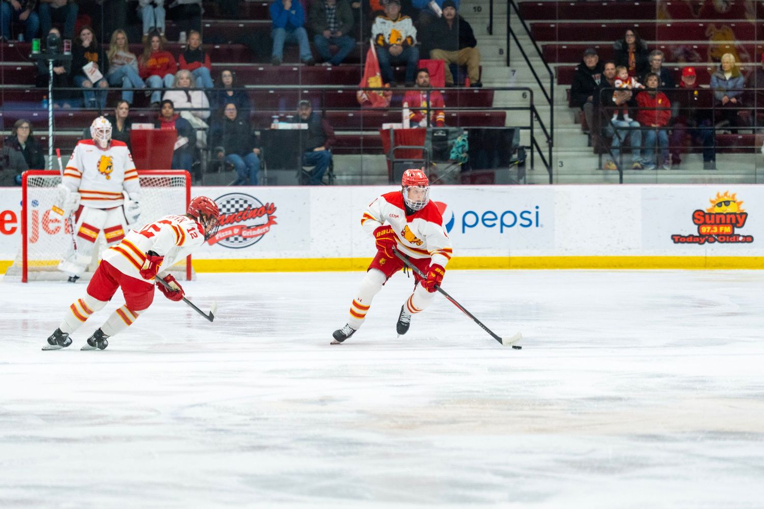 Hockey players in red and white jerseys compete for the puck during an ice hockey game.