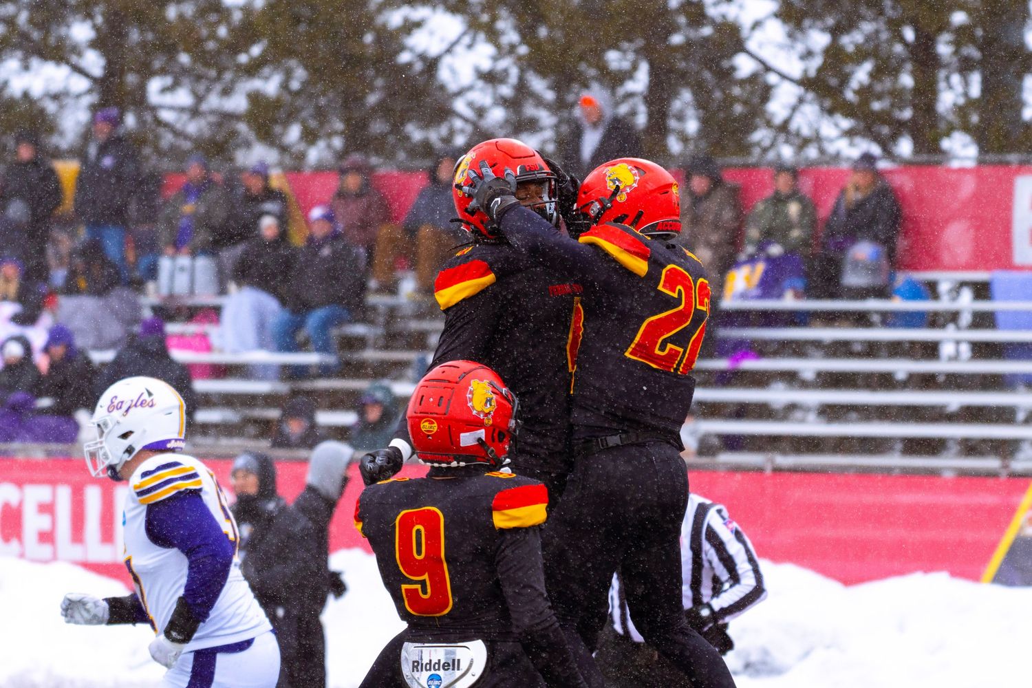 Football players compete in snowy conditions on a field during an intense winter game.