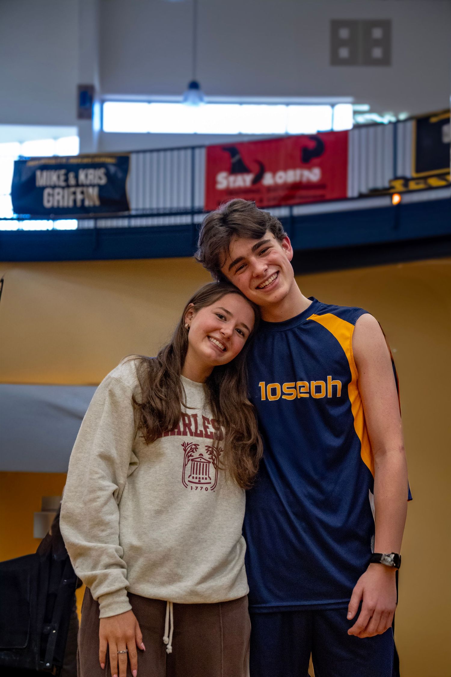 High school athletes in sports uniforms standing together in gymnasium.