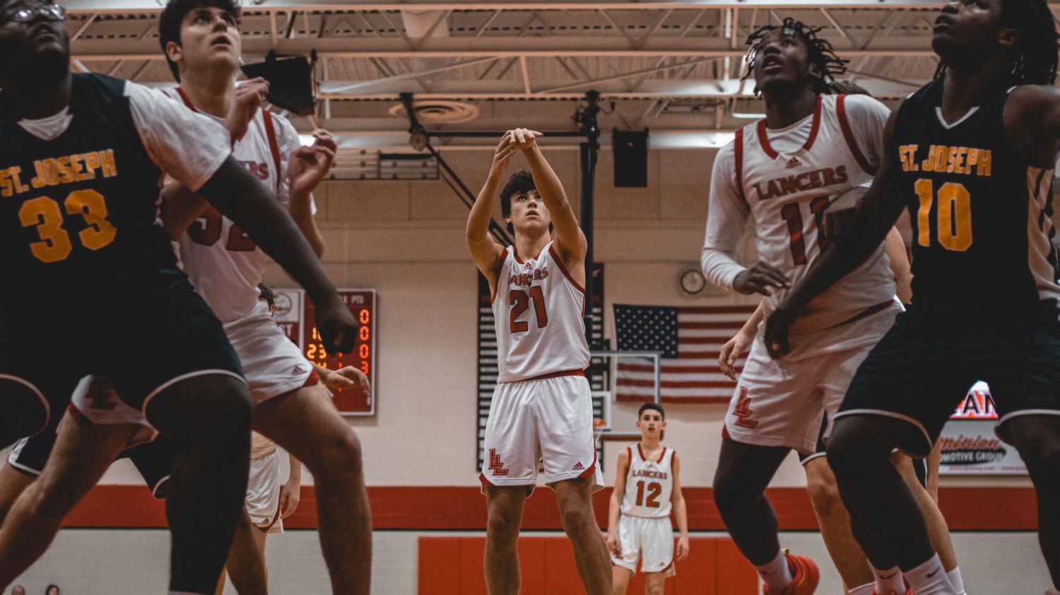 Action shot of basketball players in white and navy uniforms competing during a game.