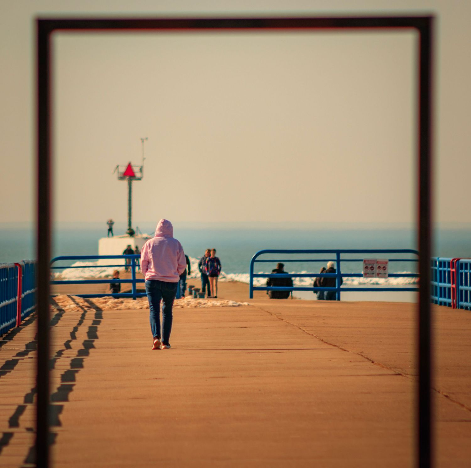 Dark silhouettes against a warm sky with blue railings on a pier or boardwalk.
