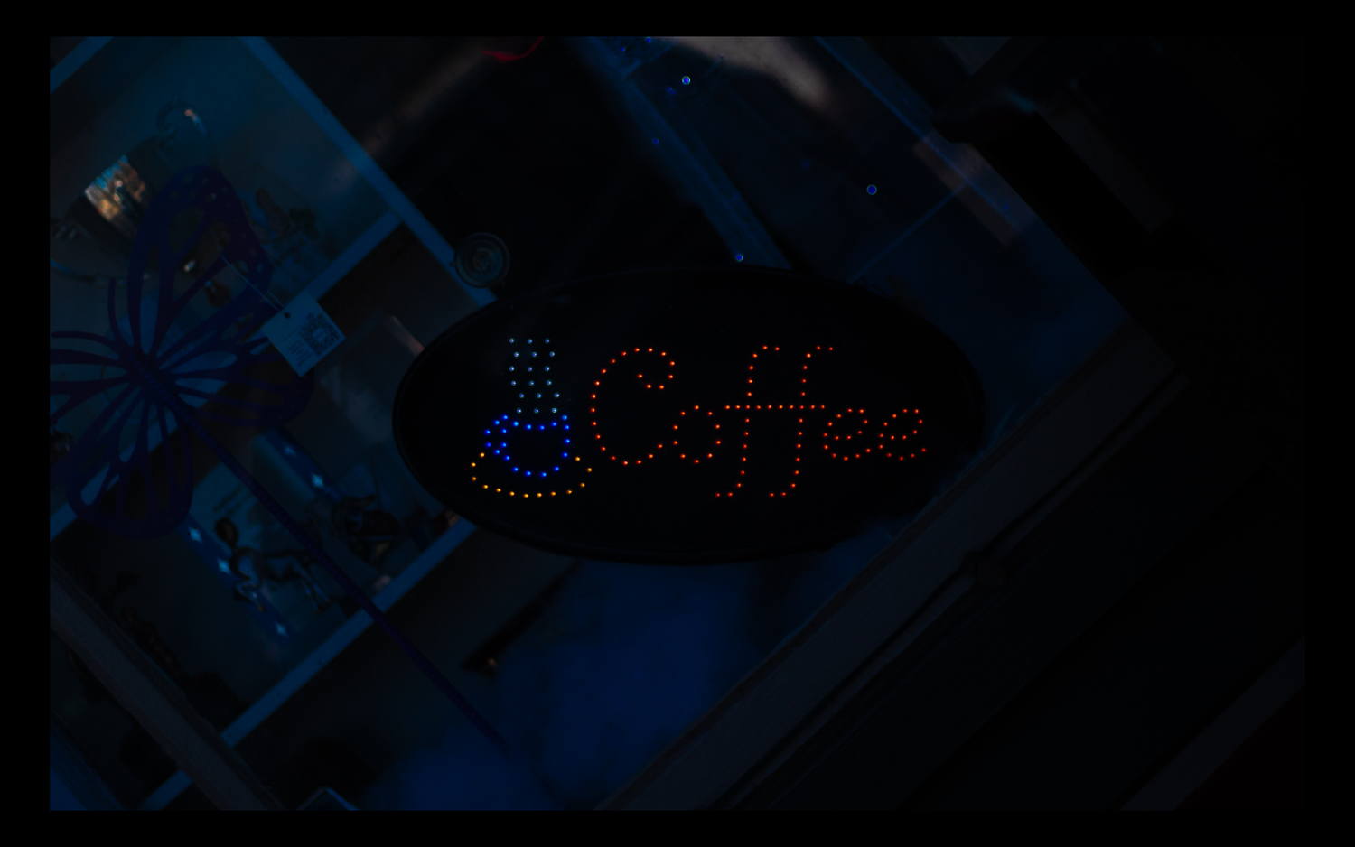 Neon blue coffee sign glowing in the darkness with heart shape detail.