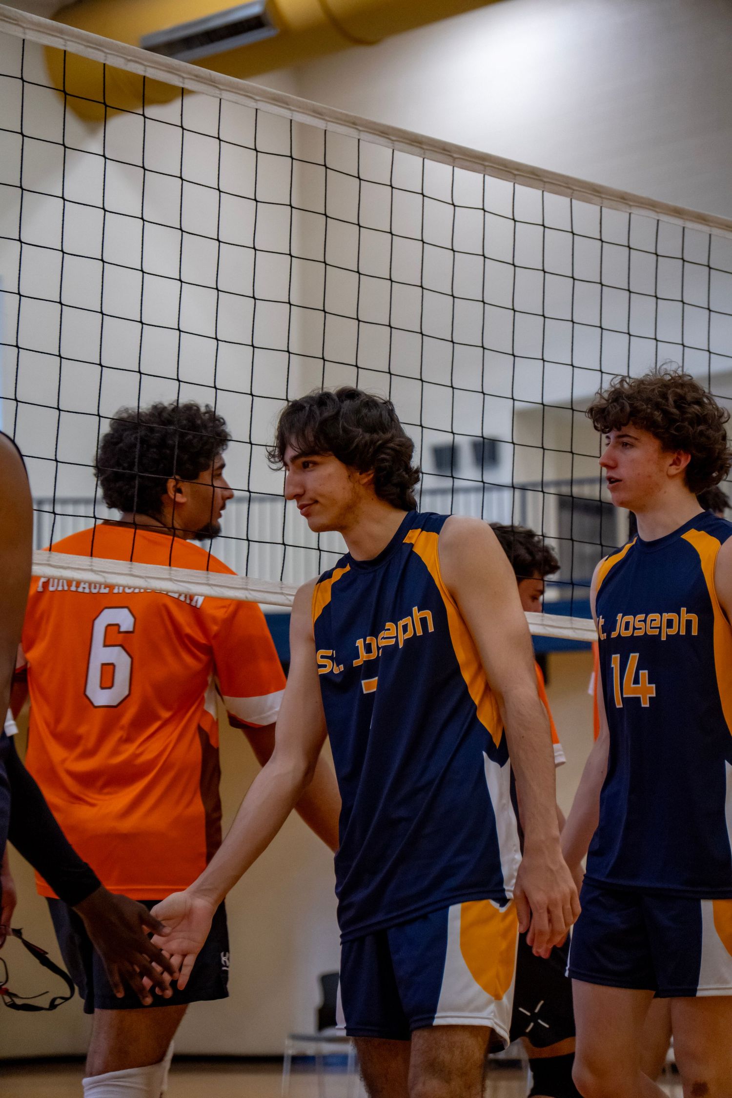 Volleyball players from opposing teams meet at the net during a game.