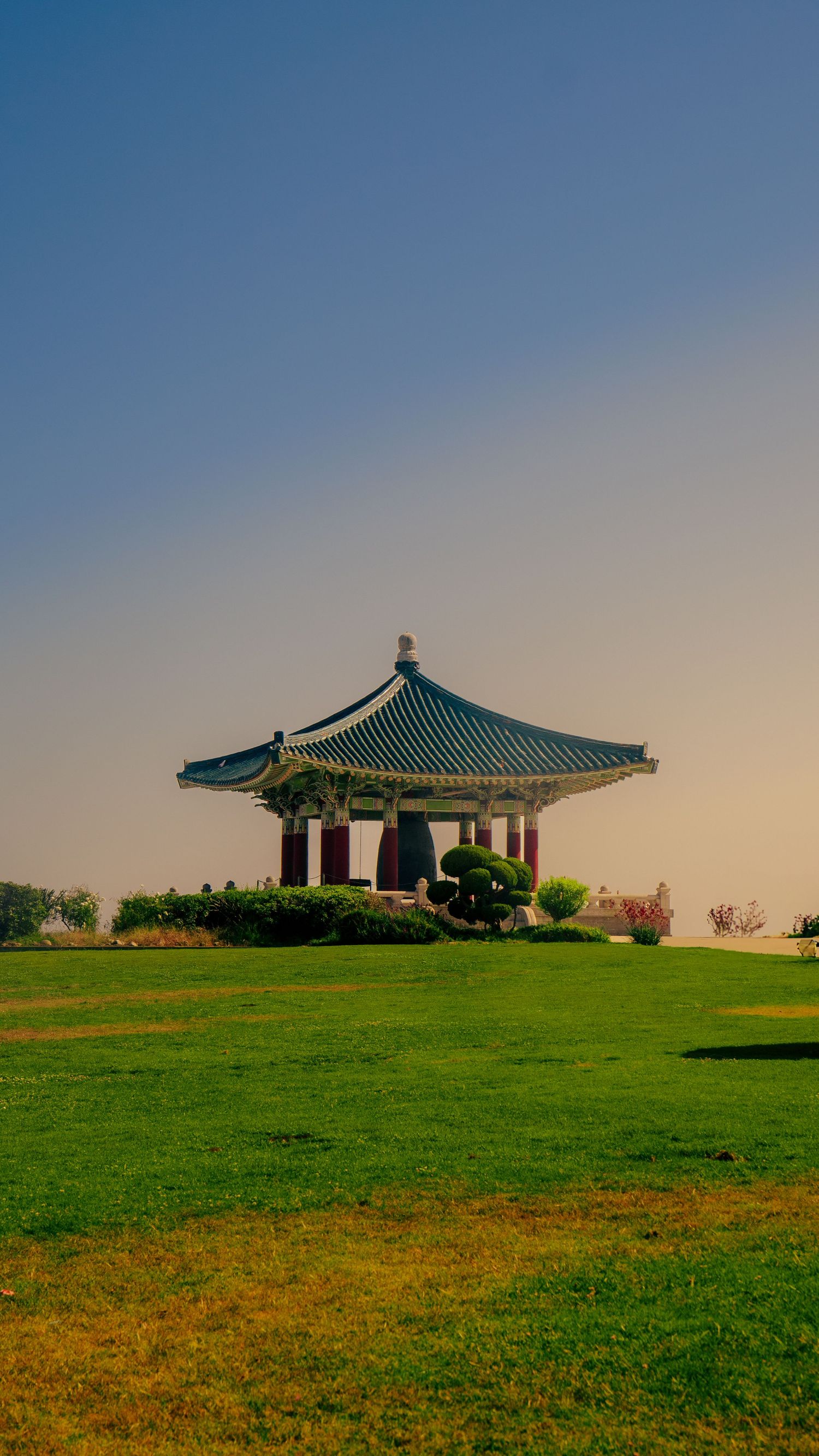 Korean pavilions with distinctive green tiled roofs situated on a grassy hillside.