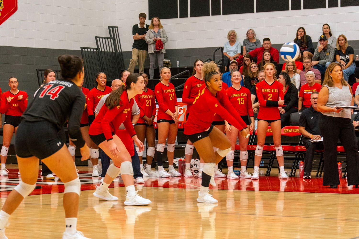 Volleyball team in red uniforms celebrates together on the court during a match.