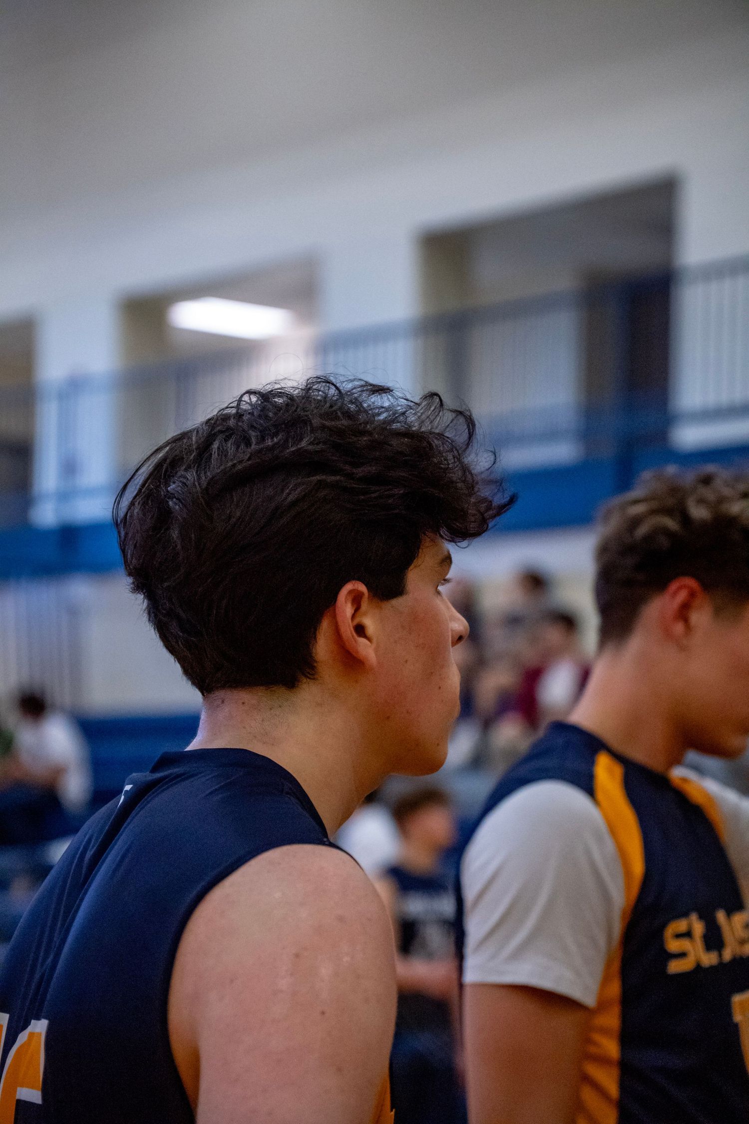 Side view of volleyball players lined up along the court during a game.