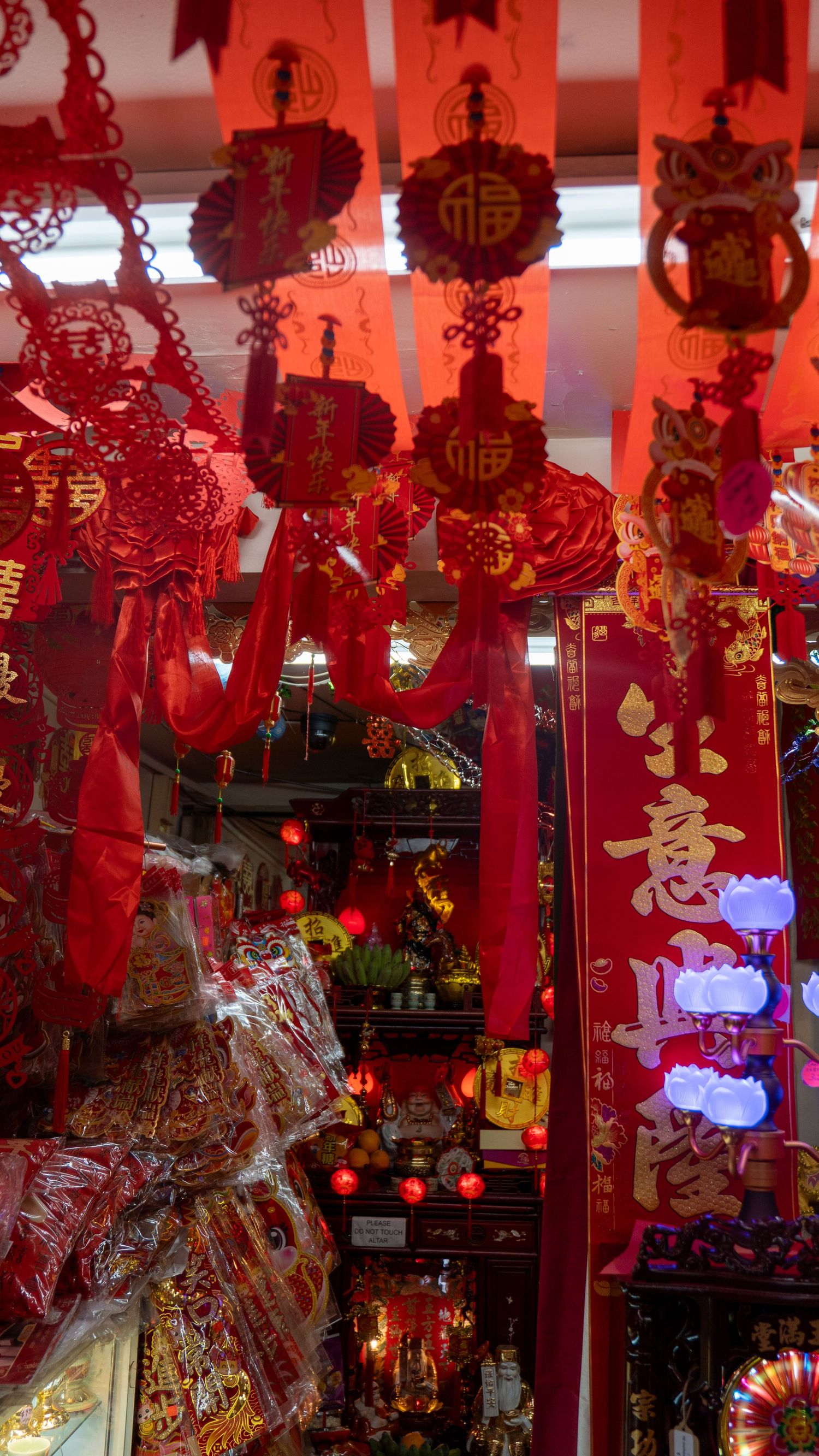 Traditional red Chinese lanterns and decorations hanging from ceiling in festive display.