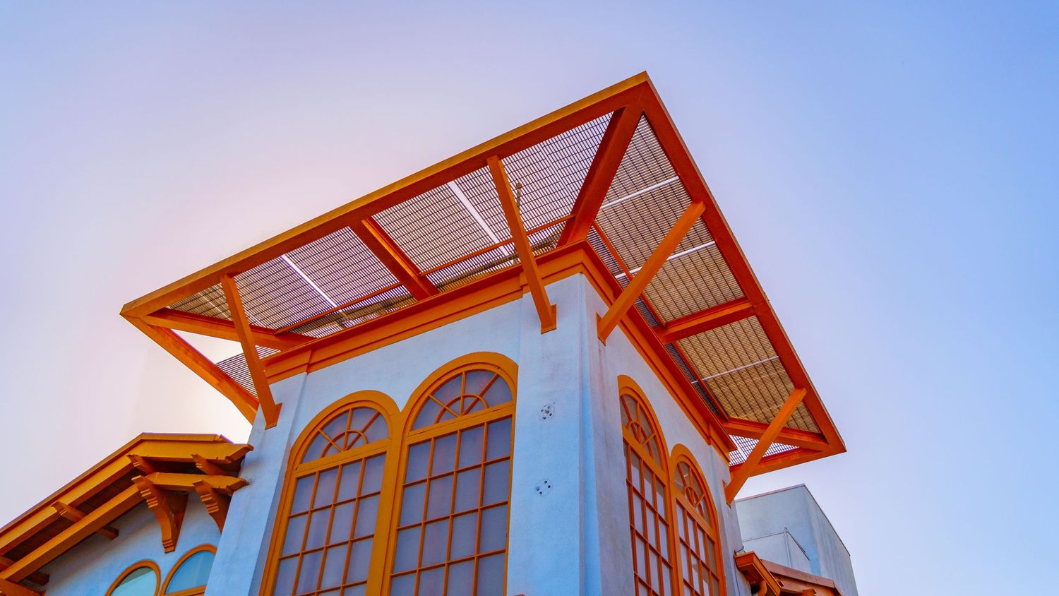 White building with orange roof and arched windows featuring Spanish colonial architectural details.