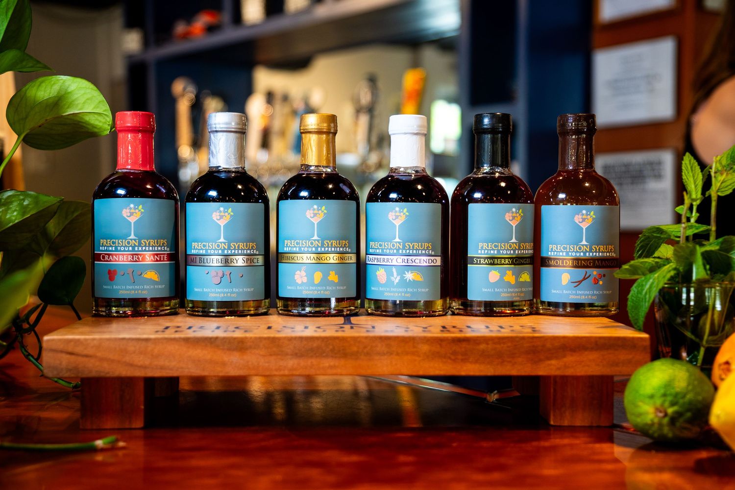 Artisanal blue-labeled spirits arranged on a wooden display stand with fresh garnishes.
