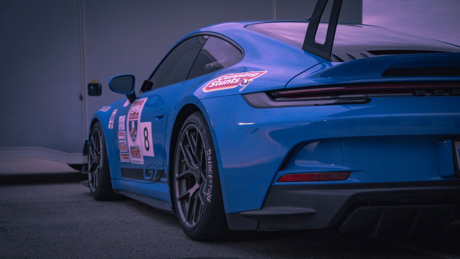 Blue Porsche GT3 race car with racing livery photographed at dusk.