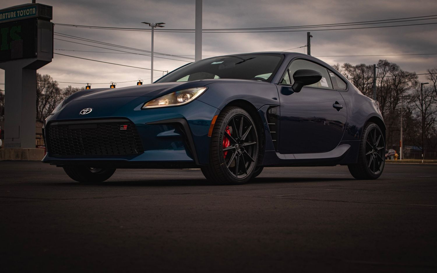 Dark blue Subaru BRZ sports car with red brake calipers at twilight.