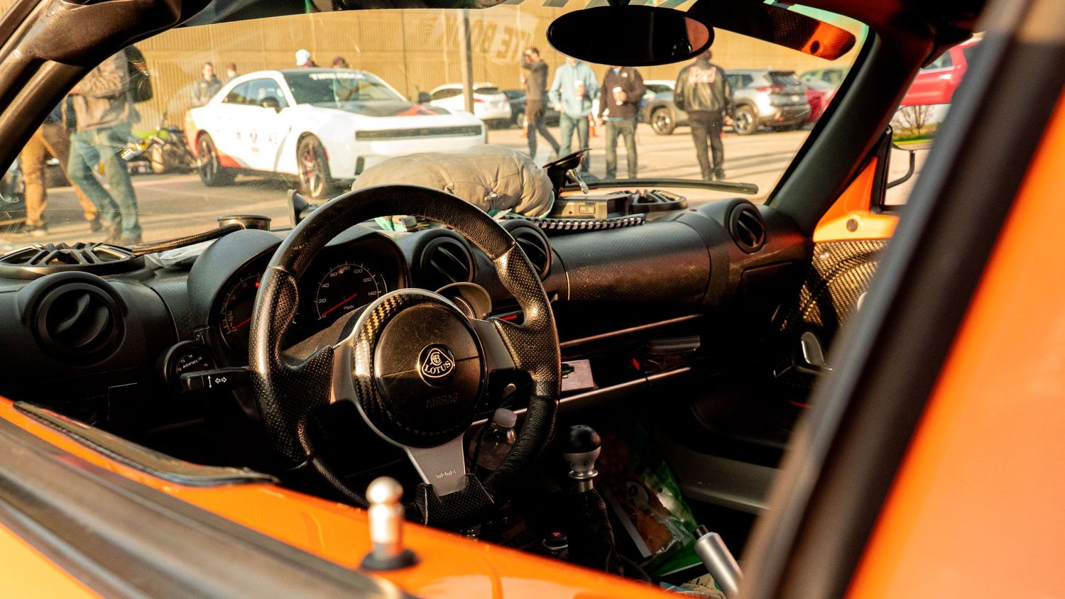 Interior view of a Lotus sports car showing the steering wheel and dashboard in orange ambient lighting.