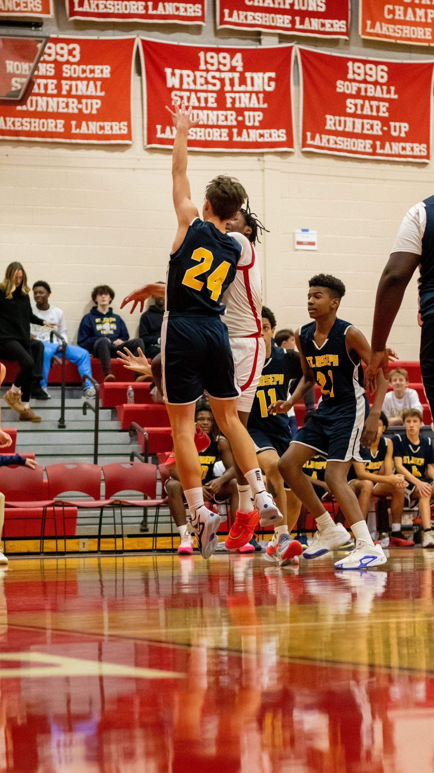 Basketball player in yellow jersey jumps for shot during competitive game.
