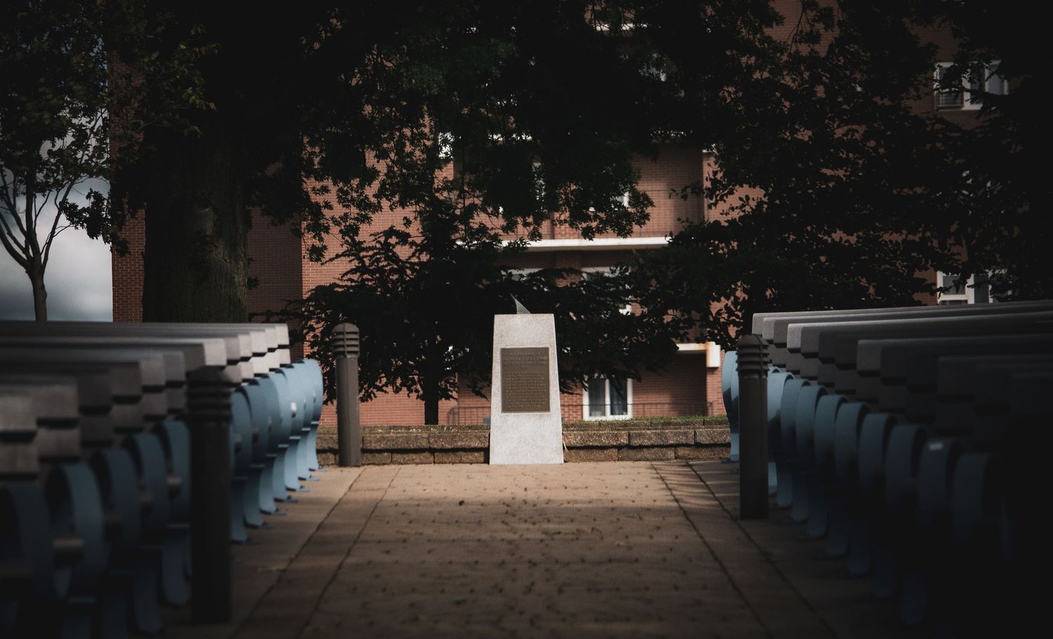 Symmetrical view of brick building entrance through tree-lined path.