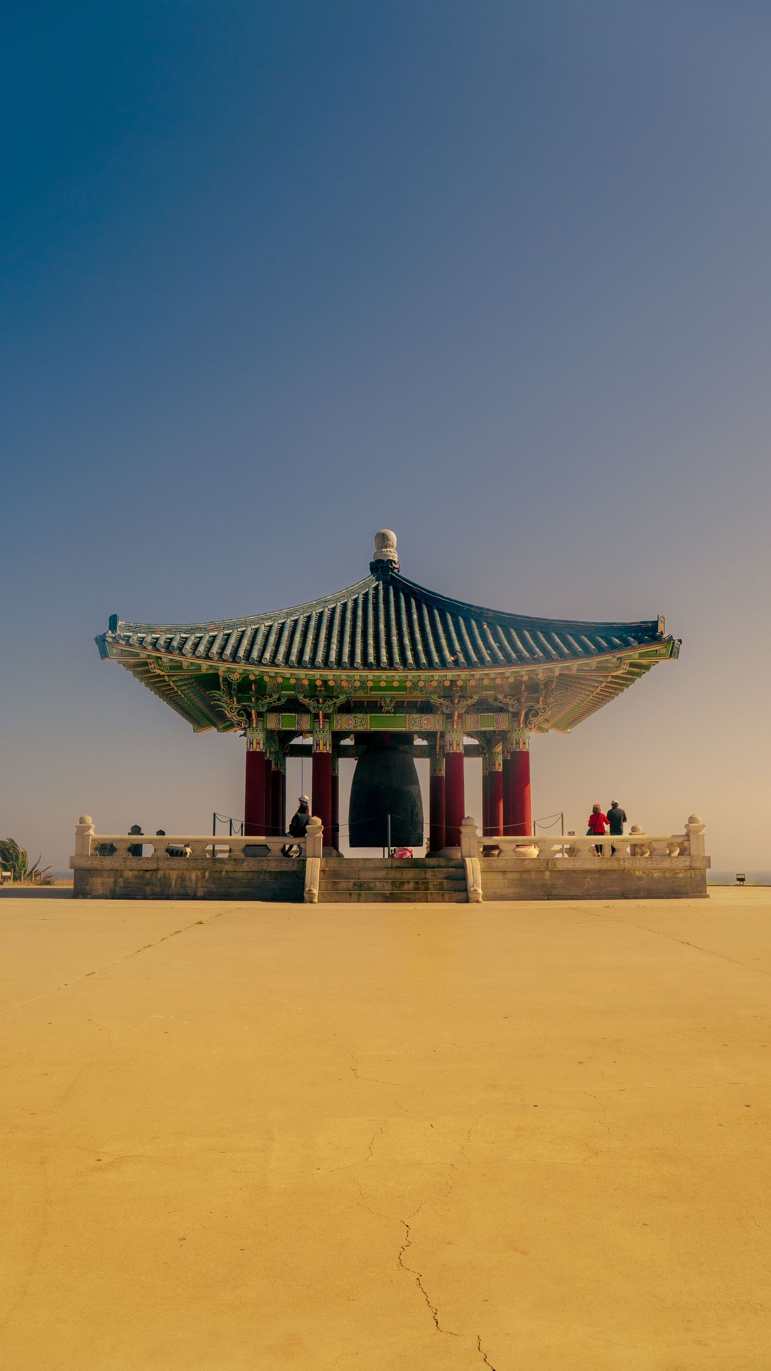 Traditional Korean pavilion with green tiled roof against clear blue sky.