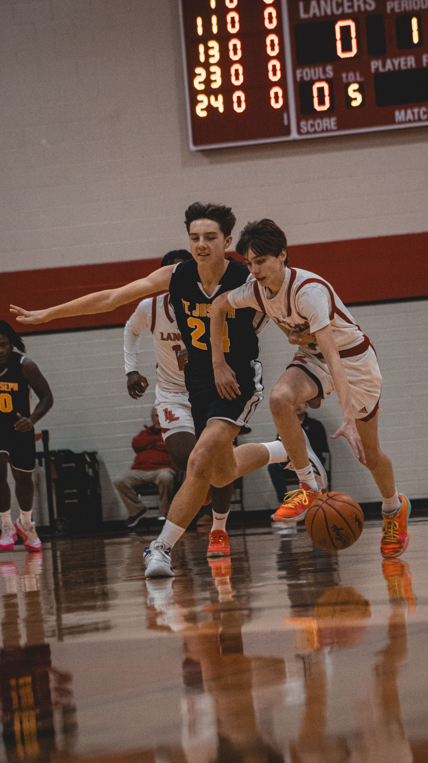 Two basketball players compete for ball control during intense game action.