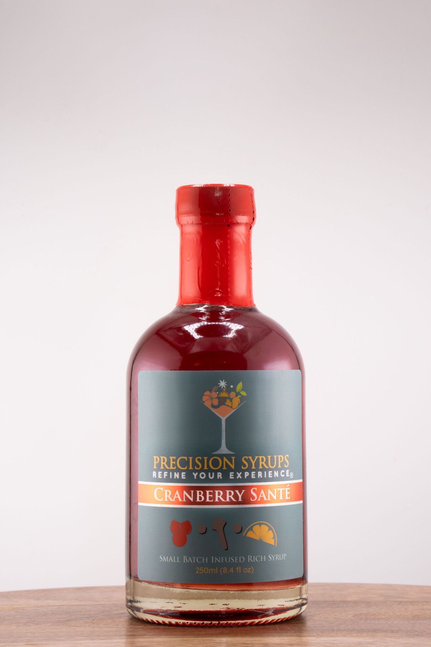 A bottle of Cranberry Sonnet Precision Syrup displayed on a wooden surface.