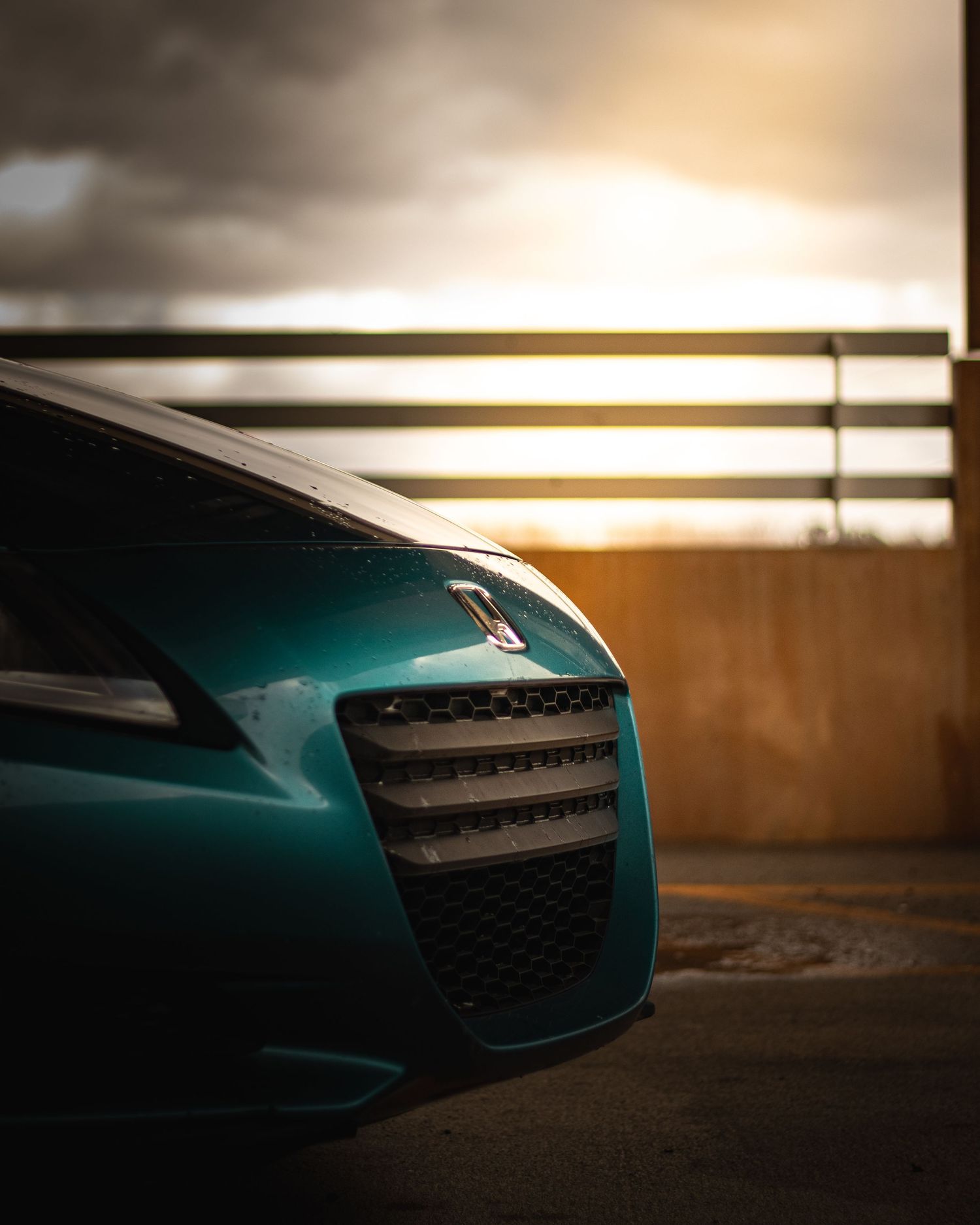 Close-up shot of a teal Honda CR-Z's front grille and headlight against dramatic lighting.
