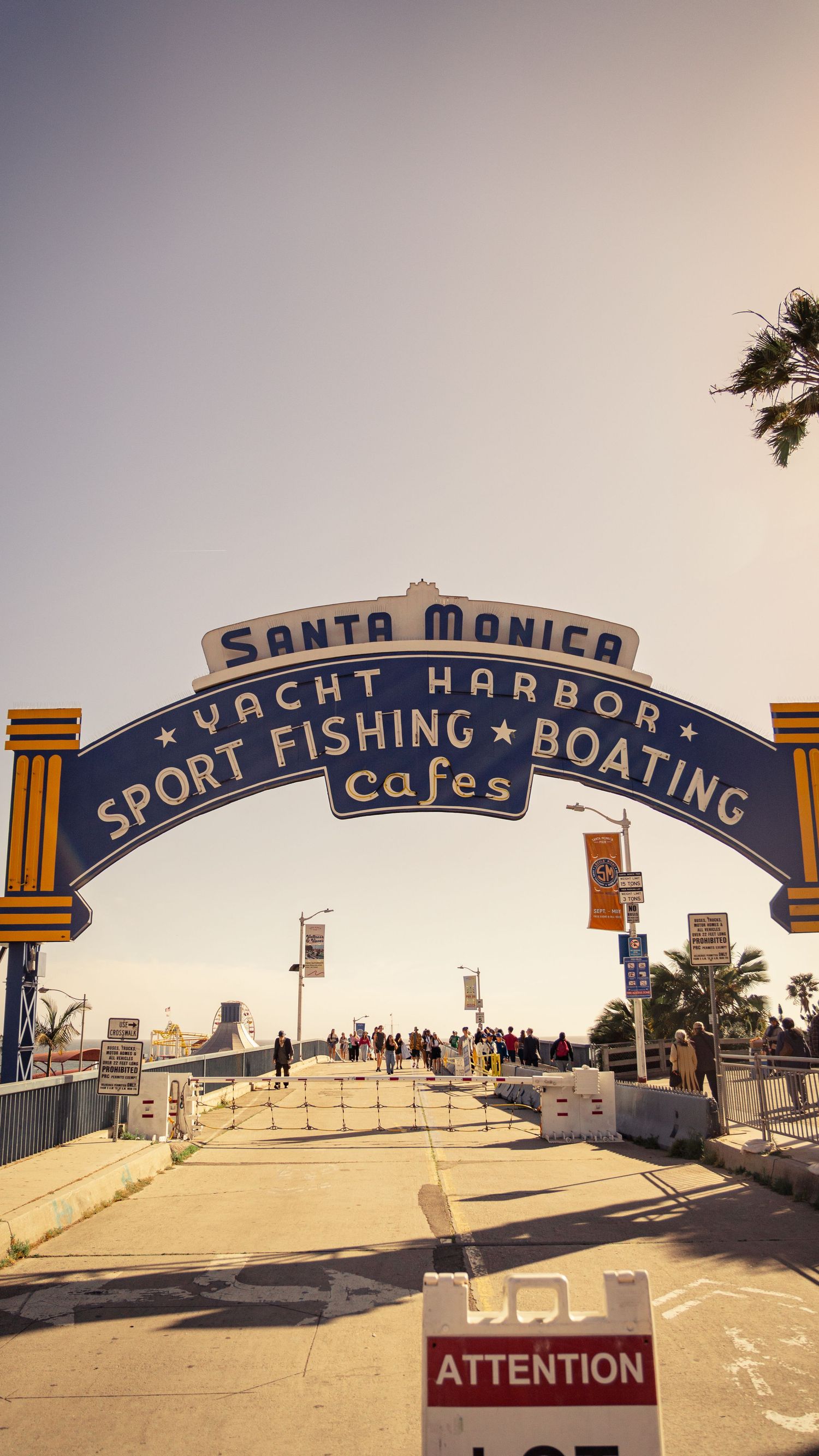Santa Monica Yacht Harbor entrance sign with palm trees and pedestrians in vintage style.