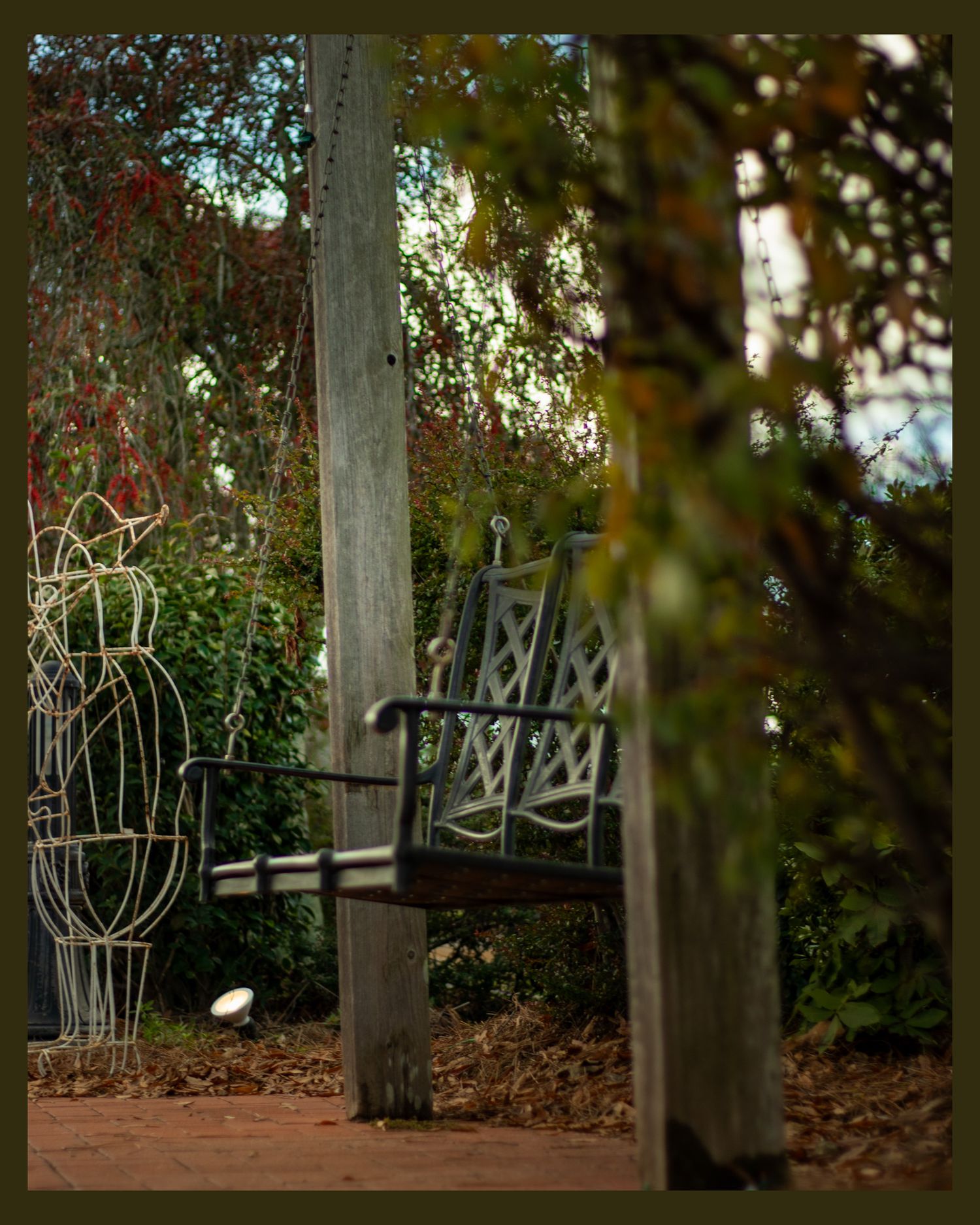Rustic wooden rocking chair on porch surrounded by garden foliage.