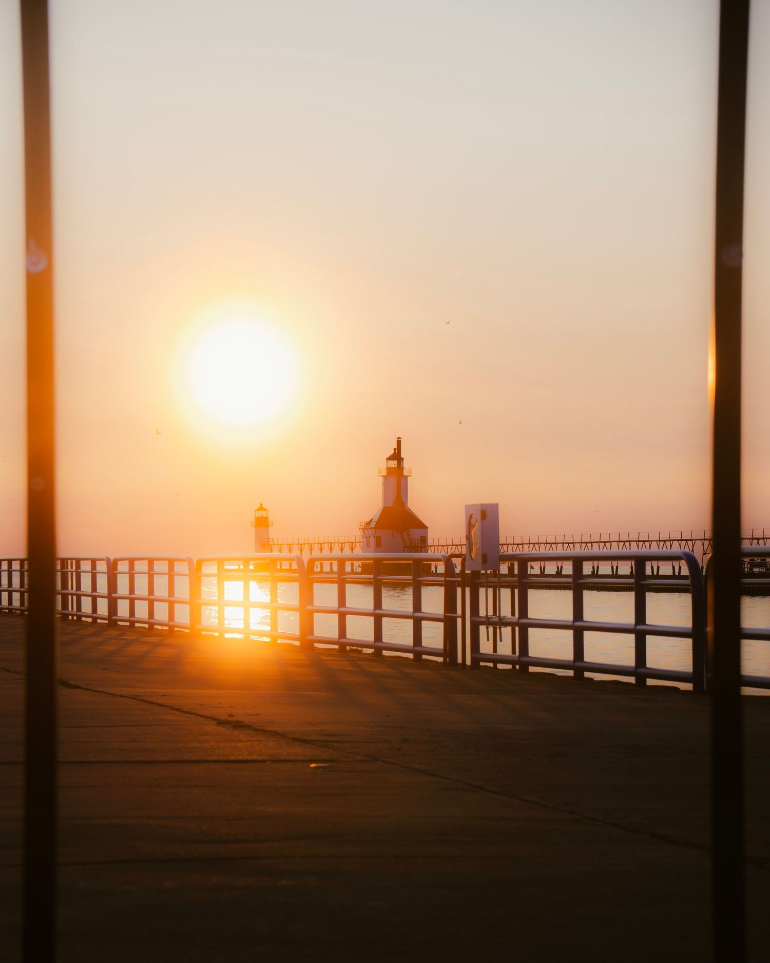St. Joseph pier lighthouse framed between posts during golden sunset.