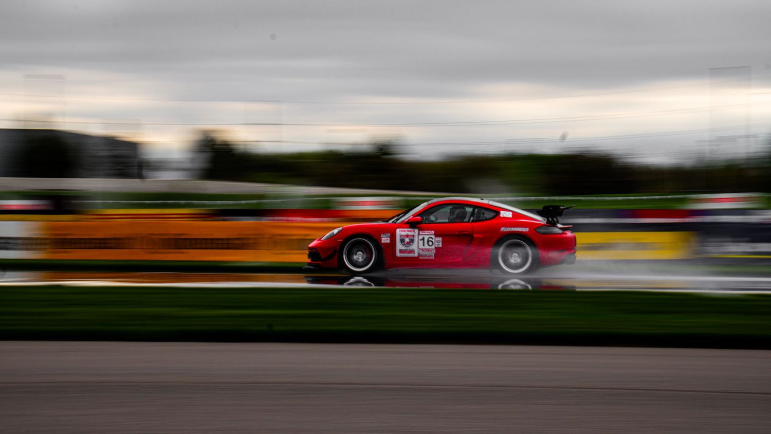 Race cars competing on a track against dramatic cloudy skies.