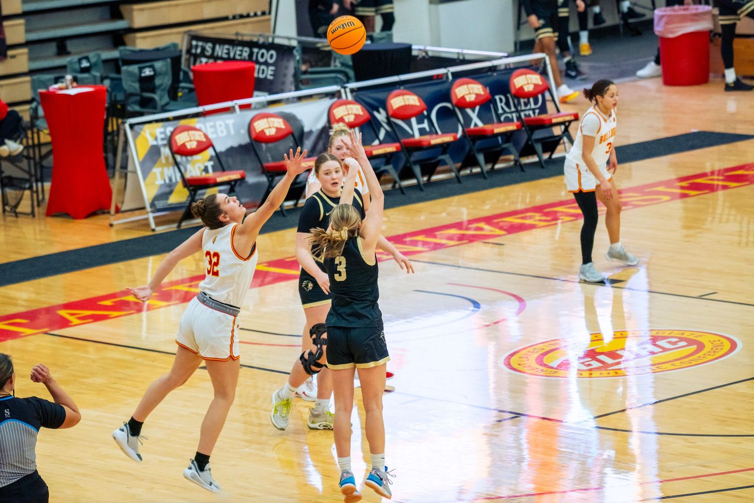 Basketball players compete for possession during an intense indoor game on a gymnasium court.