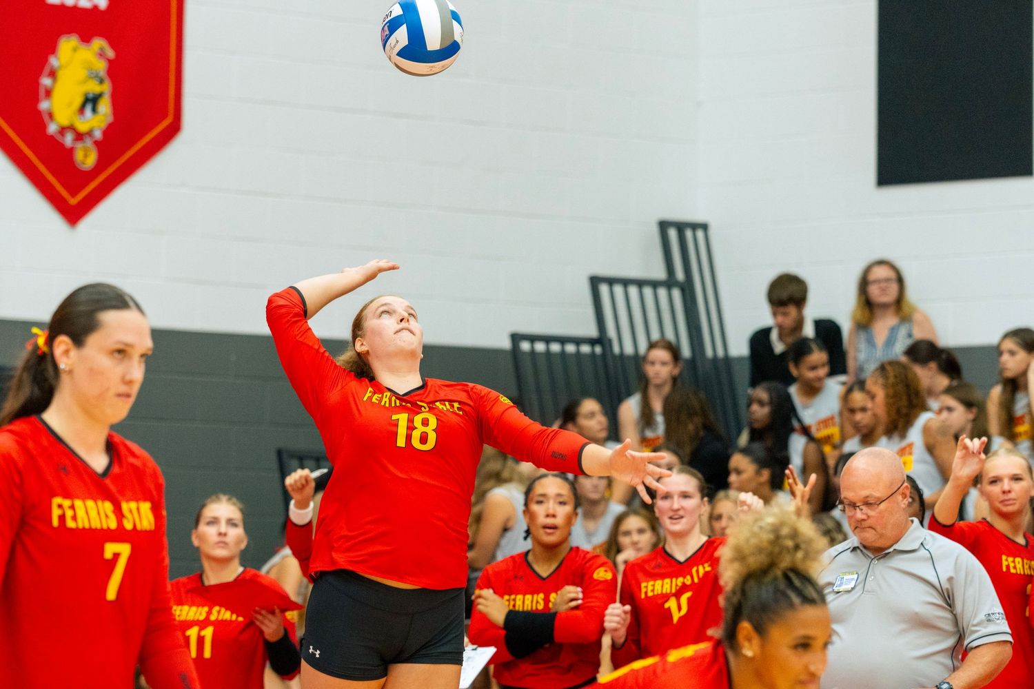 Volleyball players in red jerseys celebrate together on the court during an intense match.
