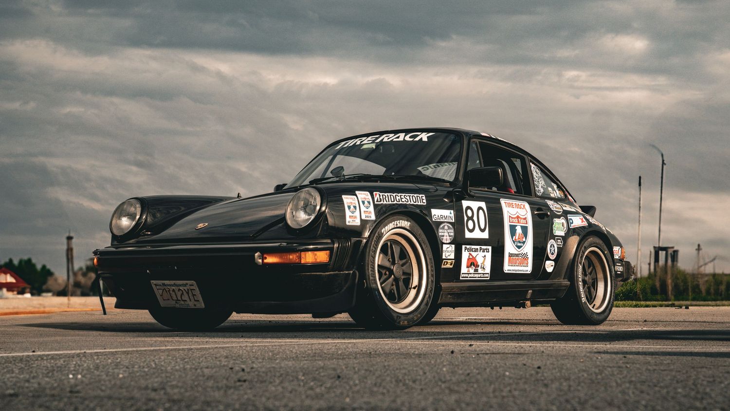 Custom performance cars parked under dramatic cloudy skies.
