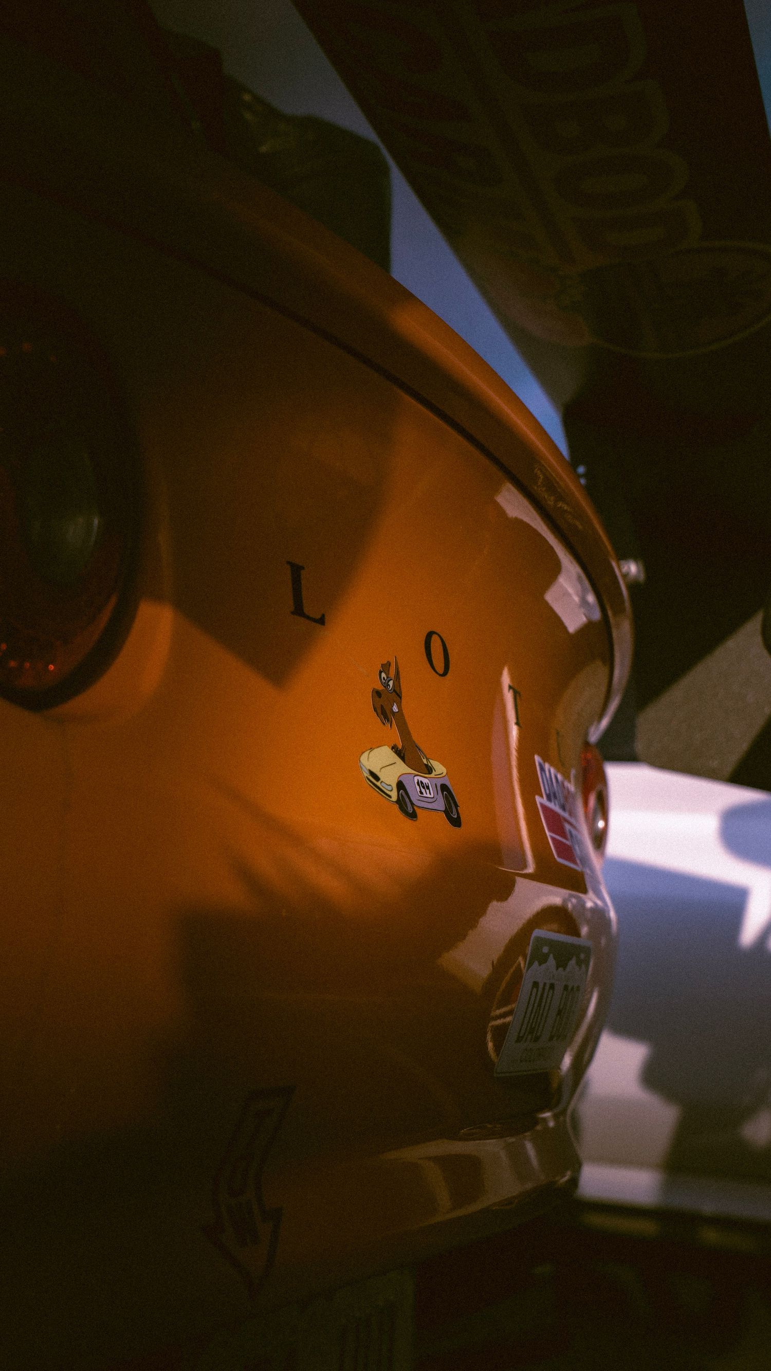 Close-up detail of orange sports car body panel with reflective surface.