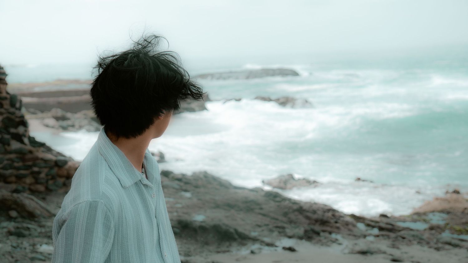 Dramatic coastal seascape with waves crashing against rocky shoreline.