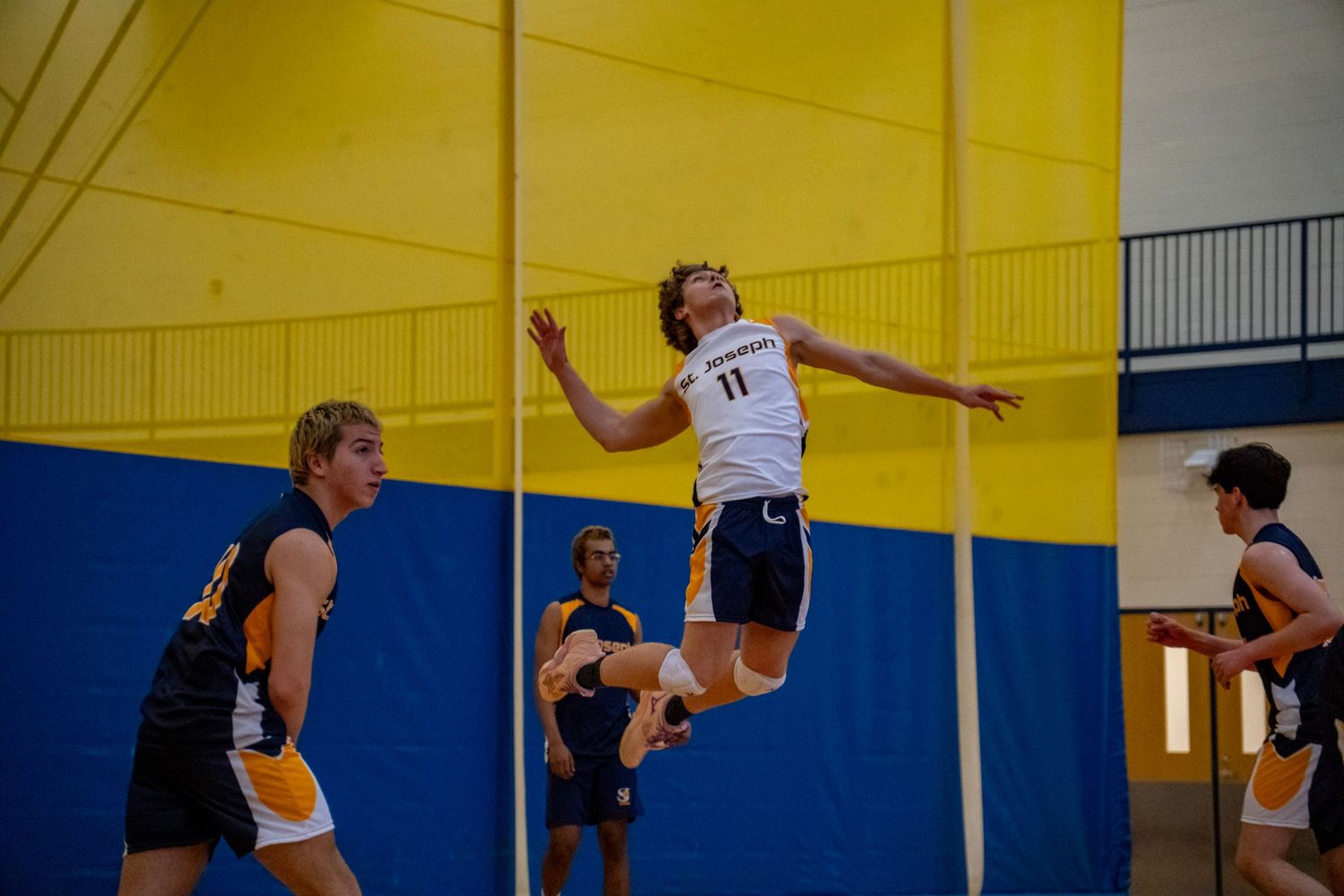A volleyball player executes a powerful jump serve during an indoor match.