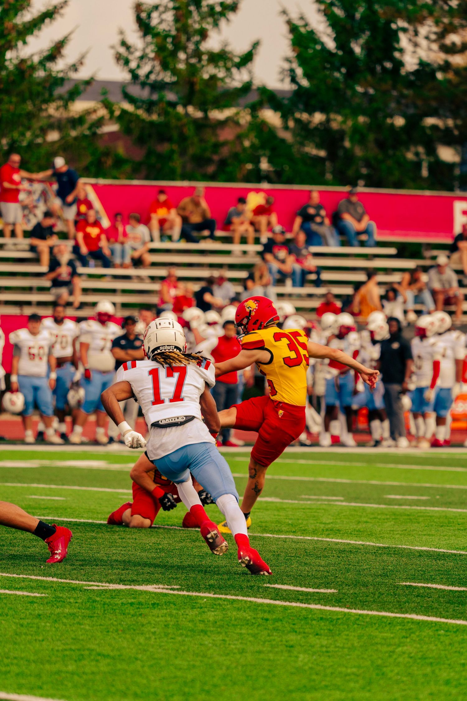 Football player dives to make a dramatic tackle attempt during an intense game on the grass field.
