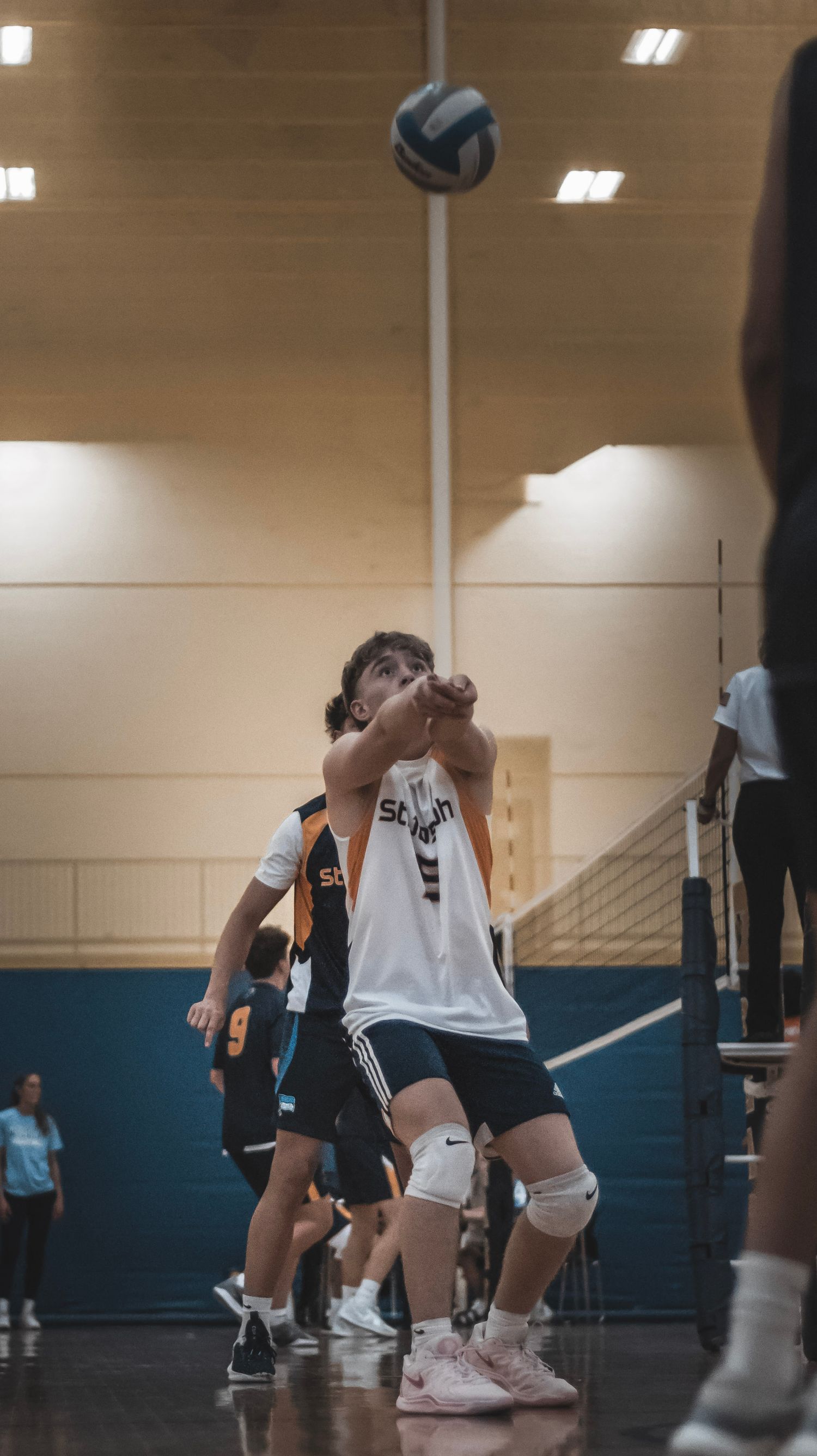 A volleyball player sets up to hit the ball during an indoor match.