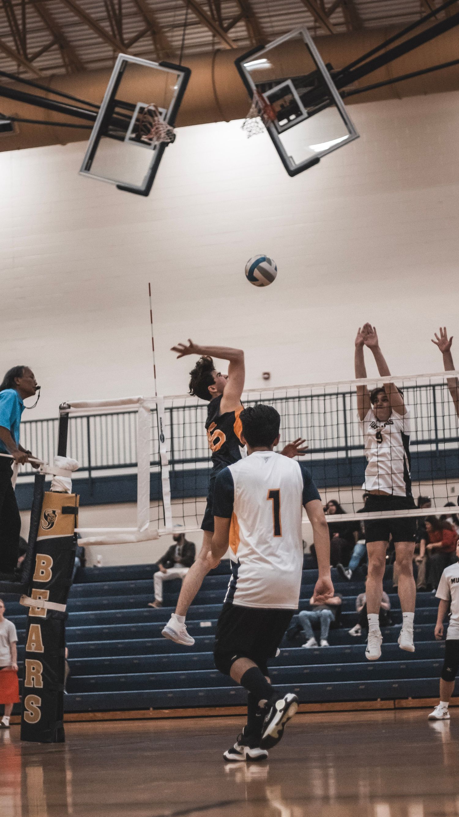 Players leap high at volleyball net during intense indoor match play.