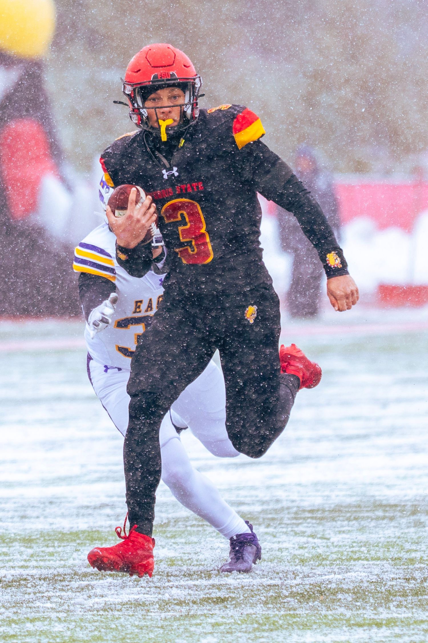Athletes slide and maneuver through snow on a football field during a winter game.