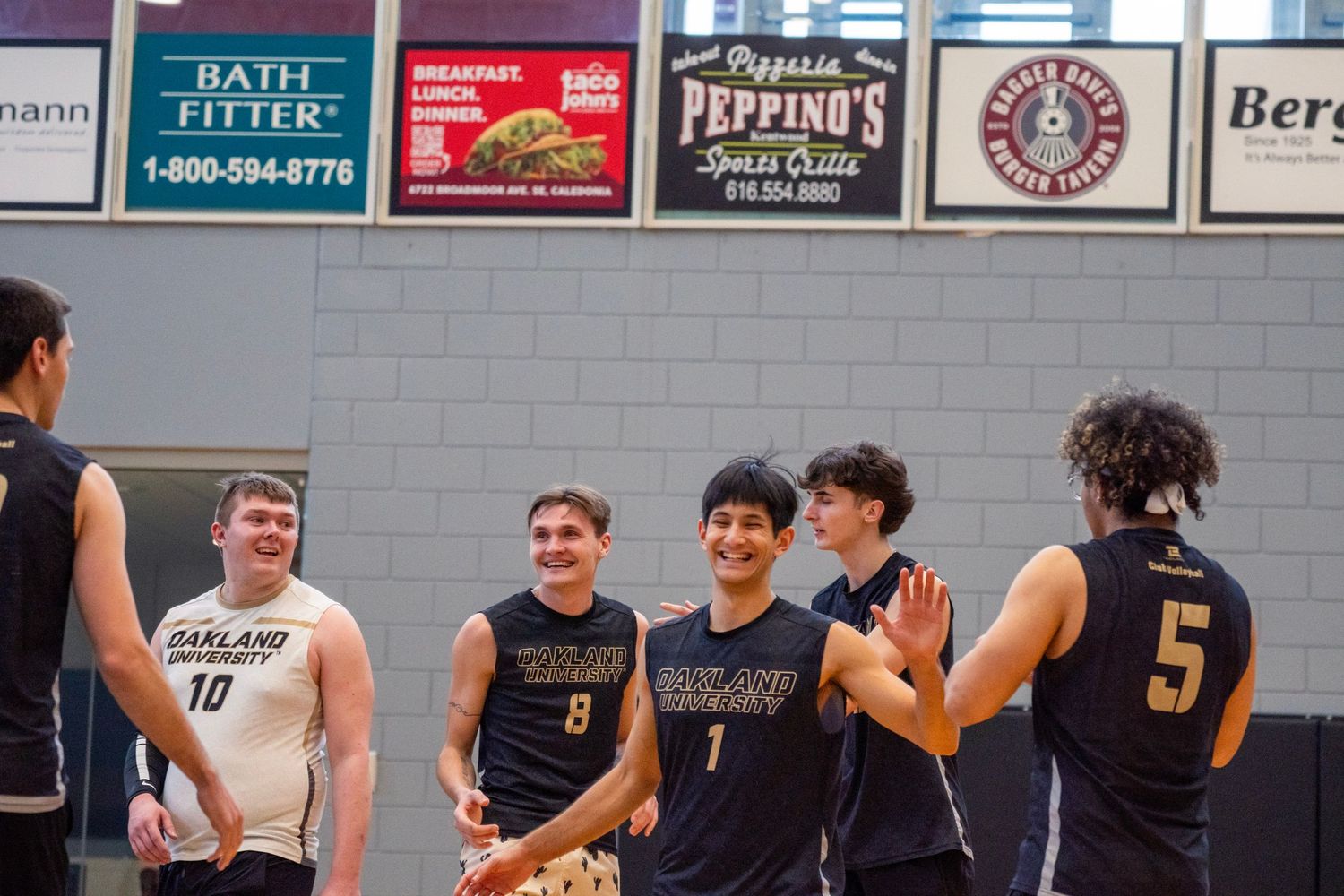 Indoor volleyball match in progress with players positioned at the net for defensive play.