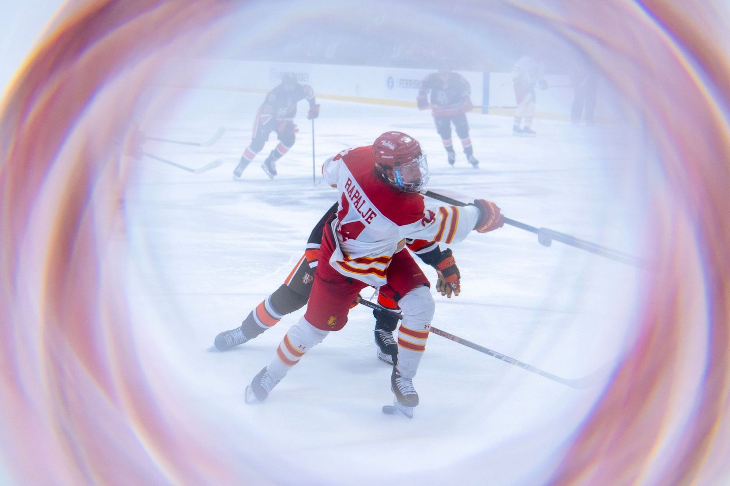 Hockey player in red and white jersey skating on ice during a game with circular vignette effect around the edges.