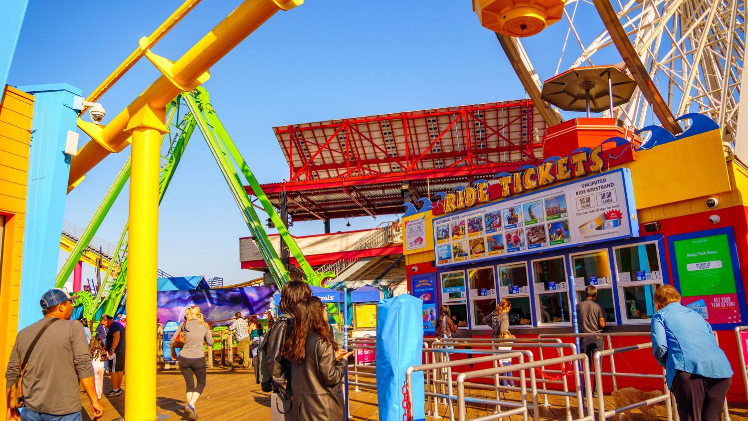 Panoramic view of carnival rides and attractions with vibrant colors and a prominent Ferris wheel.
